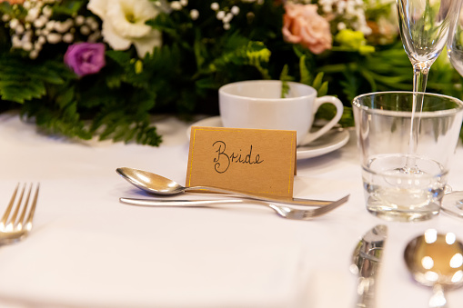 A table set up for the bride and groom at a wedding celebration, with placards, flowers and crockery