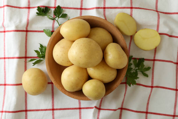 istock Wooden bowl with young potato on tablecloth 1436638687