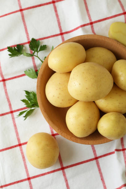 istock Wooden bowl with young potato on tablecloth 1436639485