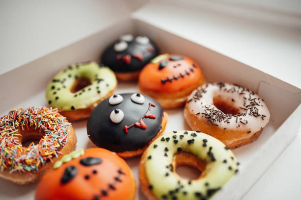 istock Assortment of halloween monsters with funny faces donuts in box at home interior 1436640007