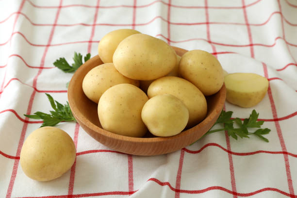 istock Wooden bowl with young potato on tablecloth 1436640220