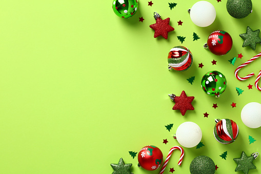 Red and green Christmas ornaments on pastel green background. Xmas greeting card template, Happy New Year banner design. Flat lay, top view.