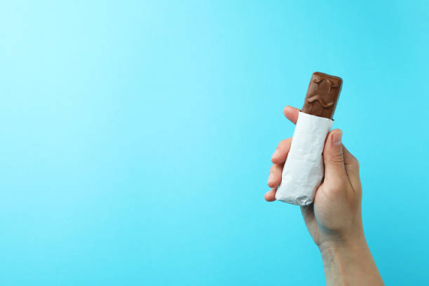 istock Female hand holds tasty candy bar on blue background 1436643129
