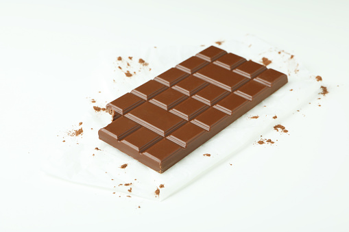 Tasty chocolate bar on paper on white background