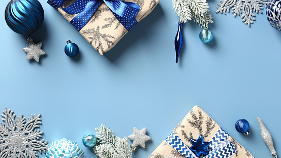 Christmas frame made of gift boxes, fir branches, silver and blue decorations on pastel blue background. Flat lay, top view.