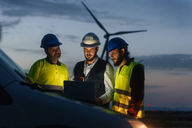 istock Electrical Engineer and technical industry workers discussing project of electricity wind power station, planing renewable energy factory at night 1436657907