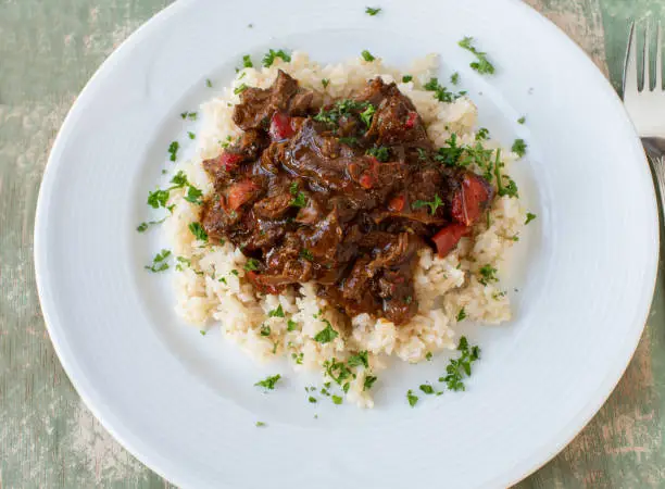 Homemade healthy and low fat beef ragout or beef stew with brown rice. Delicious meat for fitness, diet or healthy eating. Served isolated on plate from above