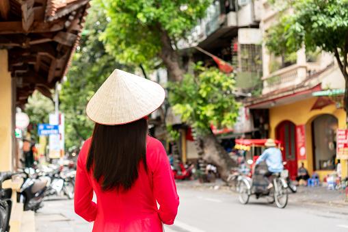 Asian tourist woman is wearing Non La (traditional Vietnamese hat) and Ao Dai (traditional Vietnamese dress) enjoy sightseeing in Hanoi city Vietnam. Copy space