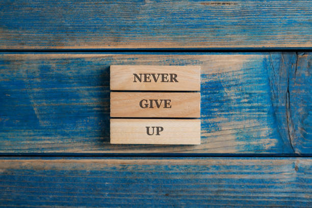 istock Never give up sign spelled on a stack of three woden pegs 1436667929
