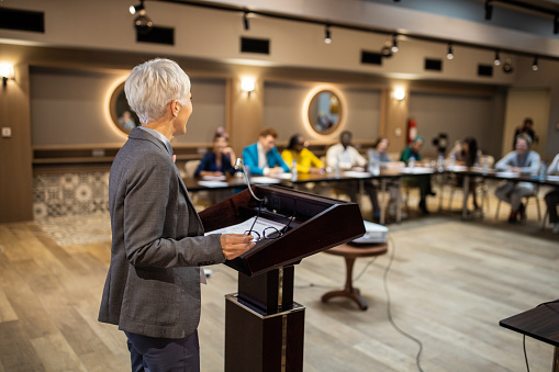 A senior businesswoman holding a speech for an audience in the conference room of a hotel