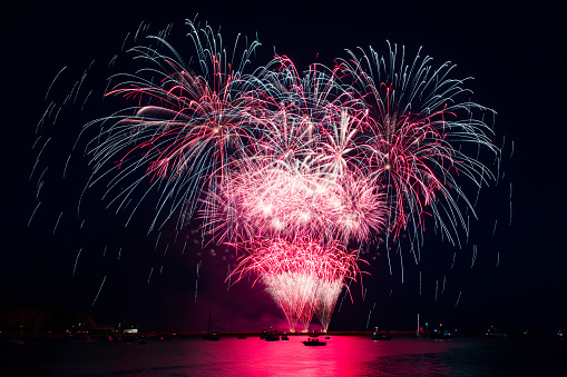 A beautiful shot of fireworks above the sea in the nighttime.