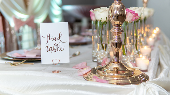 A set table for a wedding ceremony with decorations of candles and flowers with a Head Table sign