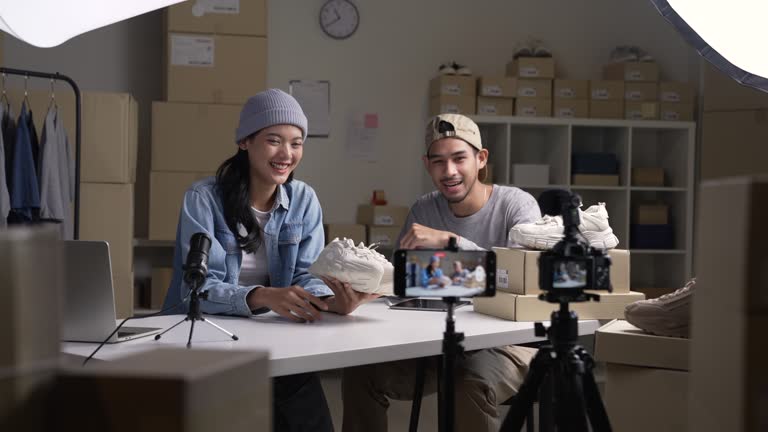 Young Asian man and woman blogger or vlogger looking at camera reviewing product and merchandise. Business online influencer on social media concept.