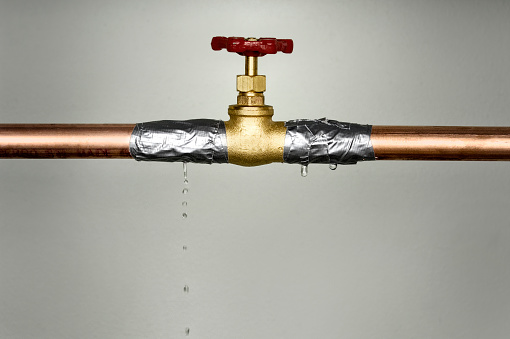 A closeup shot of the leaking water pipe with red valve