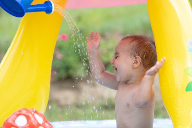 18 months old toddler enjoying a dip in her first plunge pool. summer heat outdoor fun.