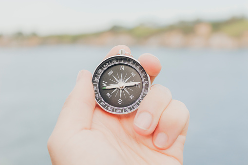 A closeup of a hand holding a compass - concept of adventure