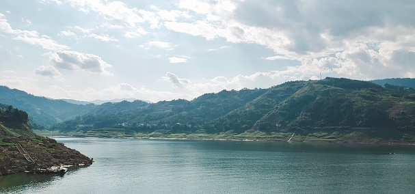 A beautiful view of the Nakdong river with green mountains under a cloudy gray sky in the background in South Korea