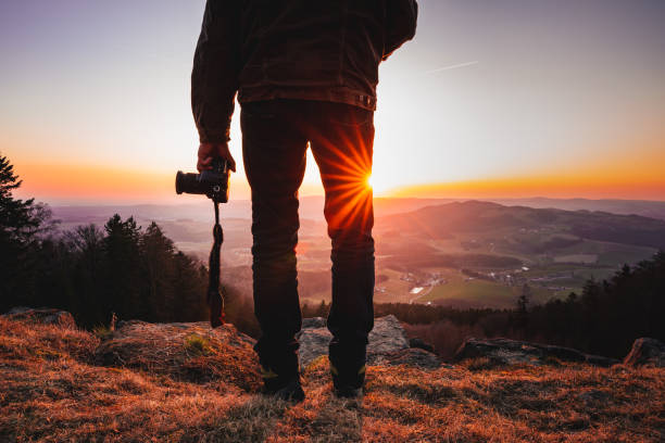 A photographer with a camera enjoying a beautiful landscape during sunset