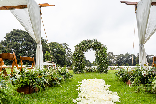 An outdoor wedding venue with a flower petal aisle on a field