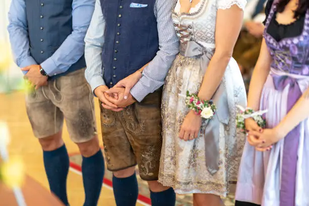 A closeup of traditional german clothes- lederhosen and dirndl dress at the wedding ceremony