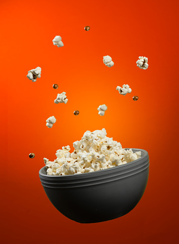 A vertical shot of a bowl of popcorn isolated on a red background