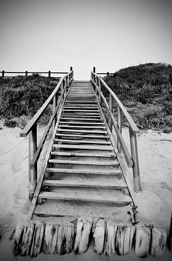 A grayscale view of a sandy beach with stairs