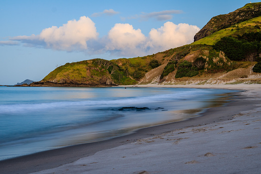 A scenic view of the cliffs at Ocean Beach against blue cloudy sky on a sunny day in Hawke's Bay, New Zealand