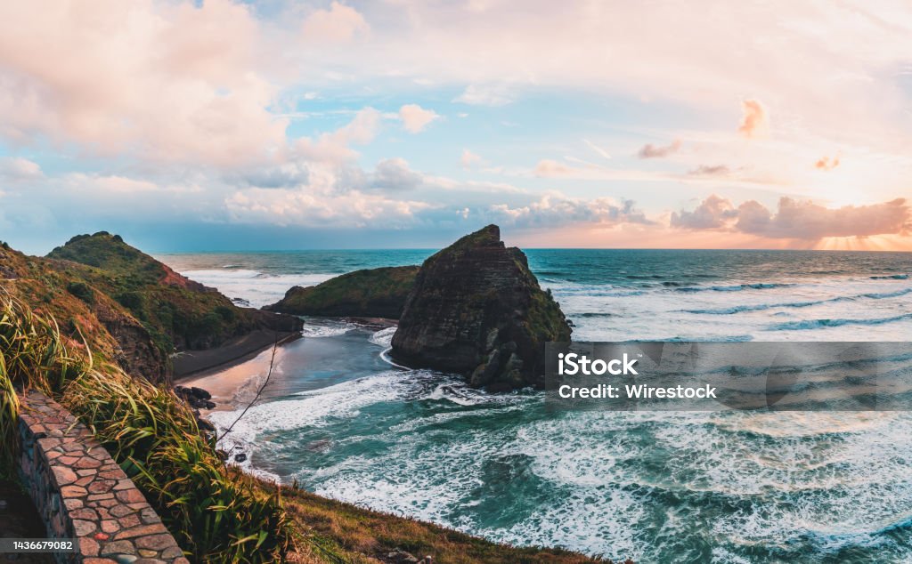 Scenic view of the rock formation and mountains against dusk sky, Piha Beach, Auckland, New Zealand A beautiful landscape view of the rock formation and mountains against dusk sky, Piha Beach, Auckland, New Zealand Piha Beach Stock Photo
