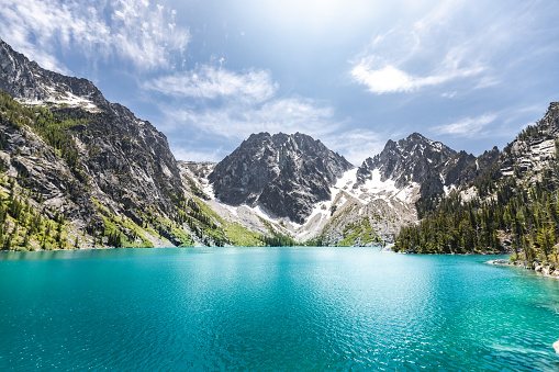 A scenic view of the Colchuck Lake against blue sky in bright sunlight in Chelan County, Washington, United States