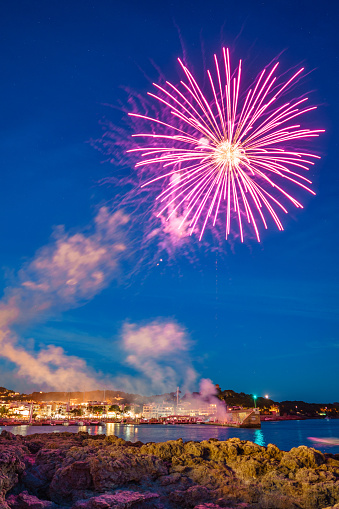 A beautiful shot of fireworks bursting in the night sky over the coastline of the city of Cala Ratjada, Mallorca, Spain