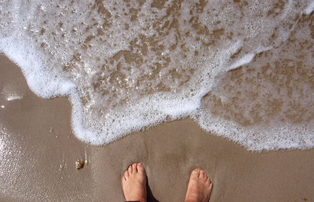 istock Legs on the beach and the sea foam 1436680676