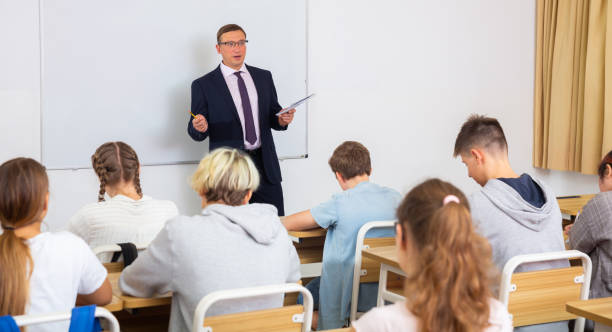 istock Male teacher lecturing to students at classroom 1436684006