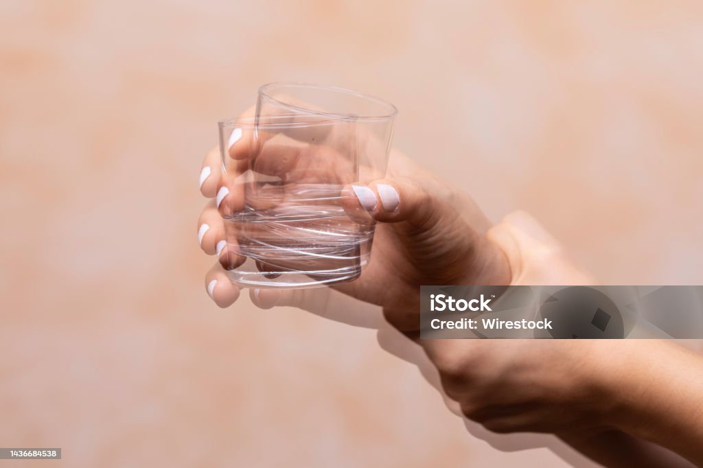 hand holding drinking glass suffering from Parkinson's disease Closeup view on the shaking hand of a person holding drinking glass suffering from Parkinson's disease Shaking Stock Photo