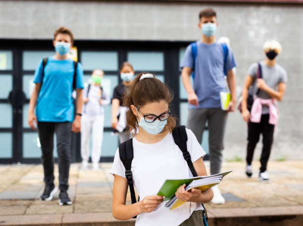 Teenage girl in protective mask with a backpack and notebooks walking in the street Teenage girl in a protective mask with a backpack and notebooks walking in the street 12 17 months stock pictures, royalty-free photos & images