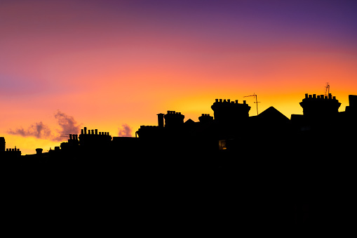 A colorful sunset illuminating the sky behind a silhouette of houses