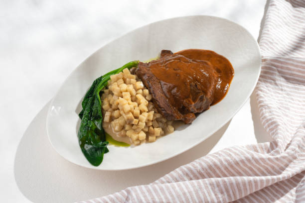 guance di manzo brasate tradizionali tedesche in salsa di vino rosso marrone con risotto al sedano su sfondo bianco - pot roast braising steak stew foto e immagini stock