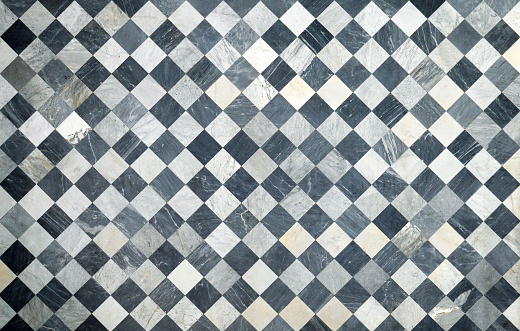 Old and worn black and white chequered floor tiles