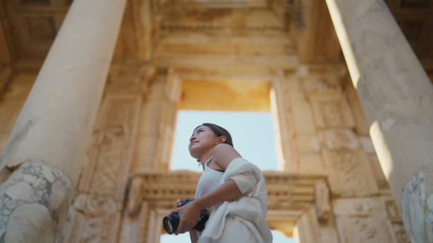 歴史的な古代の町で写真やビデオを撮っている若い女性観光客 - celsus library ストックフォトと画像