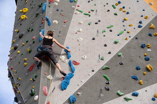 Full length of man climbing wall upside down in gym. Low angle view of young male is exercising. He is in sports clothing.