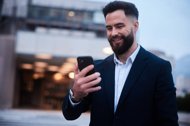 istock Smiling businessman video calling on a phone outside his building after work 1436692791