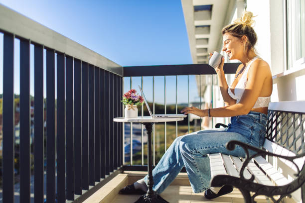 istock Young woman using laptop on balcony 1436693565