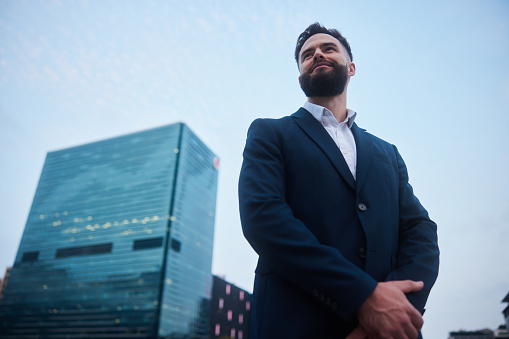 Low angle view of a confident young businessman standing outside of an office building in the city after work