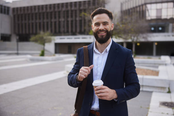 istock Businessman with a takeaway coffee smiling outside on office building 1436694224