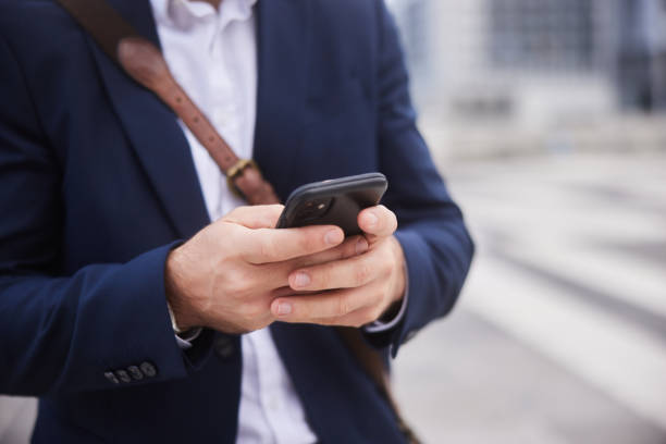 istock Businessman standing outside and text messaging on his smart phone 1436694282