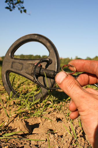 an antique gold ring in the hand of a searcher, found on an old tract with the help of a metal detector, the foreground and background are blurred with a bokeh effect