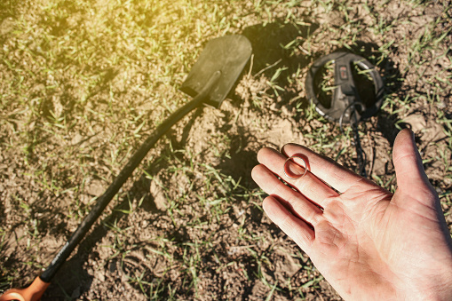 an antique gold ring in the hand of a searcher, found on an old tract with the help of a metal detector, the foreground and background are blurred with a bokeh effect