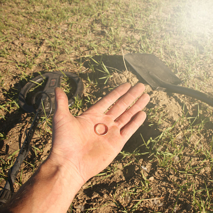 an antique gold ring in the hand of a searcher, found on an old tract with the help of a metal detector, the foreground and background are blurred with a bokeh effect