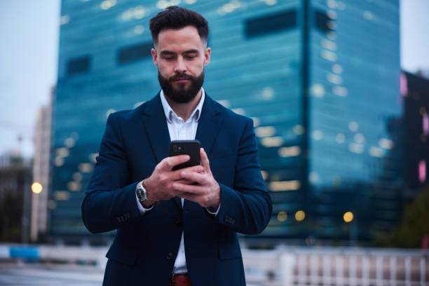 istock Businessman sending a phone text outside his building after work 1436695024