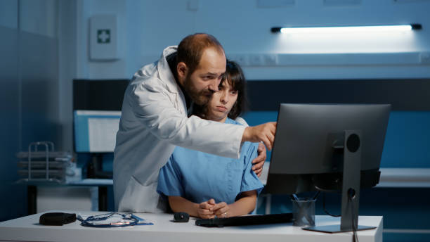 istock Nurse standing at desk typing medical expertise on computer while physician doctor touching her inappropriately 1436695242