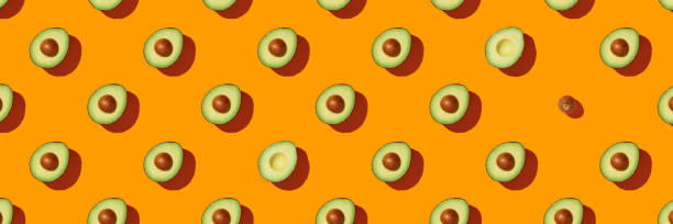 Avocado on orange background pattern top view flat lay stock photo